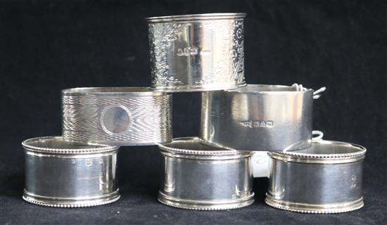 Three silver napkin rings and three plated napkin rings.